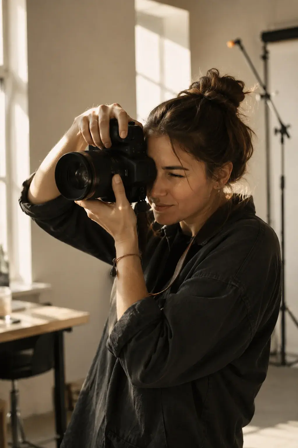 A photographer with her eye to the viewfinder, shooting in a sunlit studio